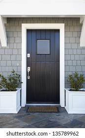 Front Door Of An Upscale Home/Vertical Shot Of A Black Front Door Of An Upscale Home With View Of Sky, Plants And Roofline.