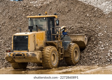 Front end loader dumping stone and sand in a mining quarry