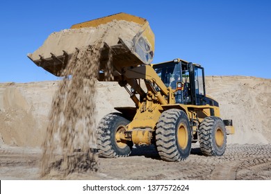 A front end loader machine tipping sand in a quarry