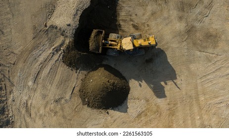 A front end loader machine tipping sand in a quarry