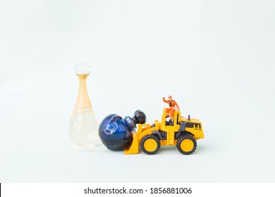 Front end loading truck clearing perfume bottles, clearance sale, miniature worker on yellow truck moving bottle on white background