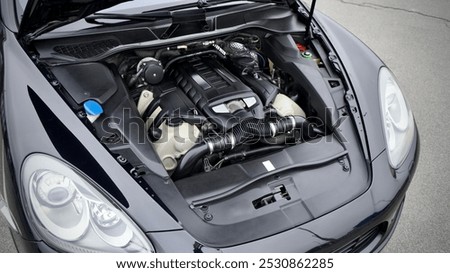 Front engine compartment of an used Germany car with clean components and assemblies plastic body under an open hood top view of auto after preparation for sale. Detailing.        