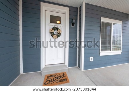 Front entrance exterior with gray vinyl wood siding and concrete flooring