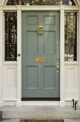 Front Entrance To A Home With Classic Design. The Door Has A Large Brass Knocker And An Elegant Frame. Vertical Shot.