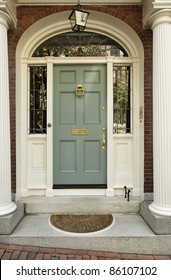 Front entrance to a home with classic design. The door has a large brass knocker and an elegant frame. Vertical shot.