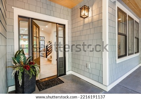 Front entry door of a modern home showing interior staircase and porch 