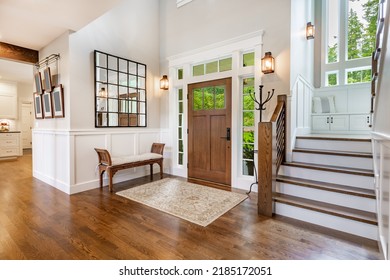 front entry foyer of a luxurious home rich wood tones staircase bench with a welcoming feel - Shutterstock ID 2185172051