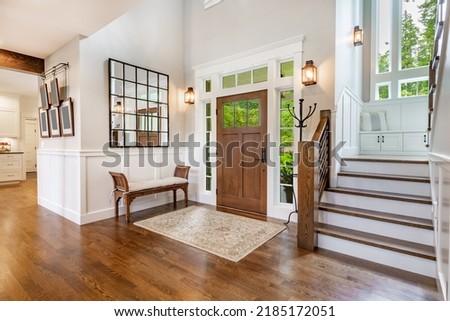 front entry foyer of a luxurious home rich wood tones staircase bench with a welcoming feel
