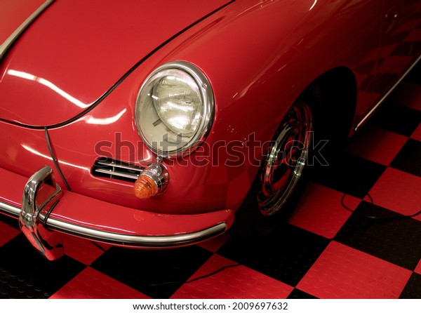 Front exterior details of antique car from fifties\
of last century, at car exhibition, parked on checkered red and\
black floor.