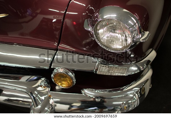Front exterior\
details of antique car from fifties of last century, at car\
exhibition, closing-up on\
headlights