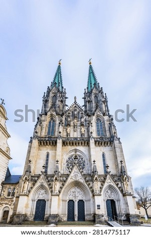 Front facade of the neo-Gothic St. Wenceslas Cathedral with two high spires under a cloudy sky in Olomouc.