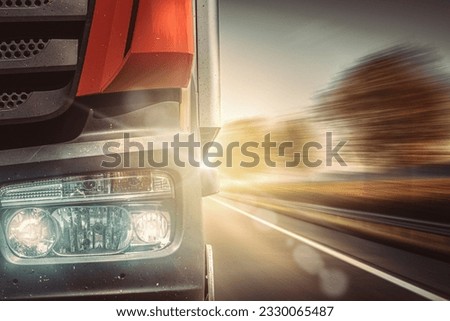 Front of fast moving truck with lights on on country road with sun rays