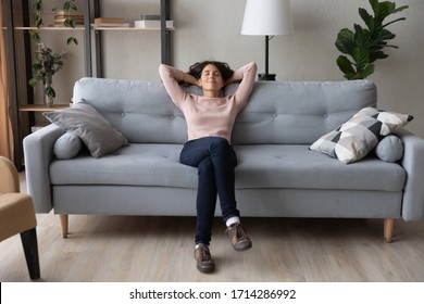 Front full length view tranquil millennial pretty woman relaxing on comfortable sofa in living room. Peaceful young lady sleeping, reducing stress, enjoying lazy weekend time on sofa alone at home.