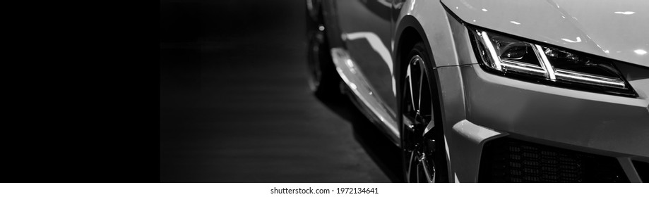 Front headlights of modern sport car black and white on black background, free space on left side for text.