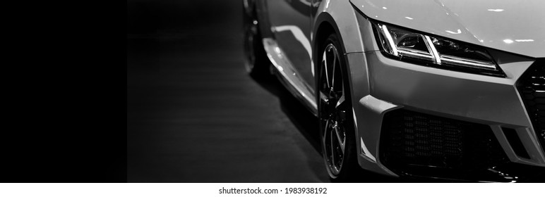 Front headlights of modern sport car black and white on black background, free space on left side for text.	