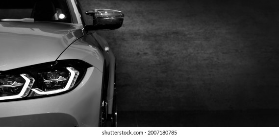 Front headlights of modern sport car black and white on black background, free space on right side for text.