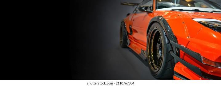 Front Headlights Of Orange Modify Car On Black Background, Copy Space	