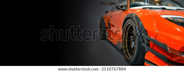 Front headlights of orange modify car on black
background, copy space	