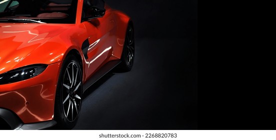 Front headlights of orange supercar on black background,copy space