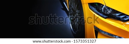 Front headlights of yellow modern car on  black background,copy space

