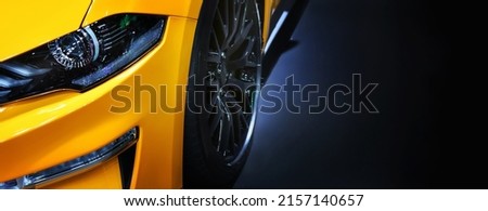 Front headlights of yellow modern car on black background