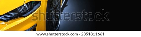 Front headlights of yellow sportcar on black background, copy space	