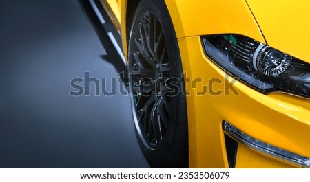 Front headlights of yellow sportcar on black background, copy space	