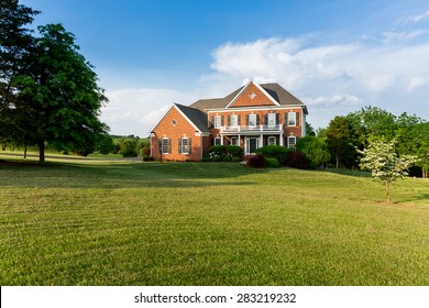 Front Of Home And Garage Of Large Single Family Modern US House With Landscaped Gardens And Lawn On A Warm Sunny Summers Day