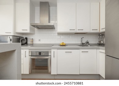 Front image with a kitchen equipped with white furniture, integrated stainless steel appliances, a small island on one side - Powered by Shutterstock