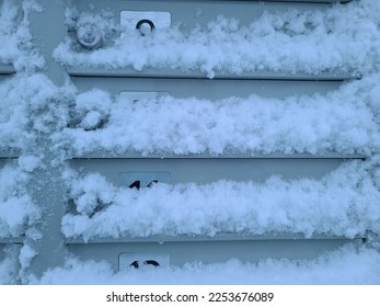 The front of a key box that is covered in snow.