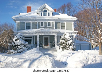 The front of a large older home covered in deep snow.