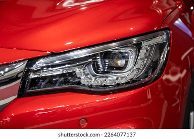 Front LED light of clean shiny red car. Detail of front Lamp. Day time running light switched off, visible shape