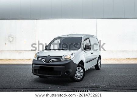 Front left side of cheap white french minivan with hubcaps