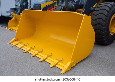 Front loader bucket. Yellow loader bucket close up. Fragment of loader. Special equipment for construction work. Special equipment for loading operations. Machinery for agricultural activities.