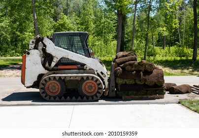 Front loader and a pallet with rolls of sod grass for installation.