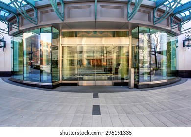 Front Of Luxurious Apartment Building, With Glass Windows And Doors.