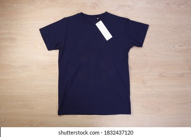 Front Navy Blue Tshirt With Label On Wooden Background