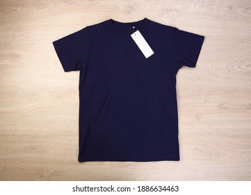 Front Navy Blue Tshirt With Label On Wooden Background