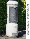 The front panel at the base of a classic Victorian style street light. Cast iron painted black and white, this vintage piece was manufactured by the now defunct Revo Tipton company.