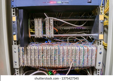  The Front Panel Of A Telecommunications Cabinet With Random Interweaving Of Wires. Communication Patch Panel For Ip Telephony.  Modems And Switches Are In The Datacenter Server Room Box.