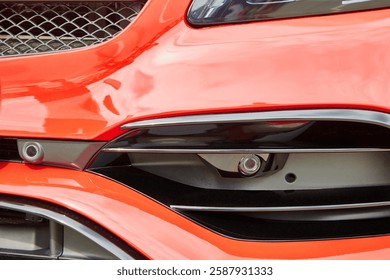 Front parking sensor on a red modern car. Car front bumper with parking sensors.