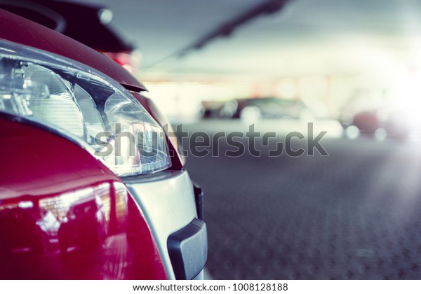The front part of a car in the light of the\
low sun under a covered parking\
area.