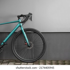 Front Part Of Gravel Bike On Grey Wall Background. Modern Brand New Bicycle For Cross Country.