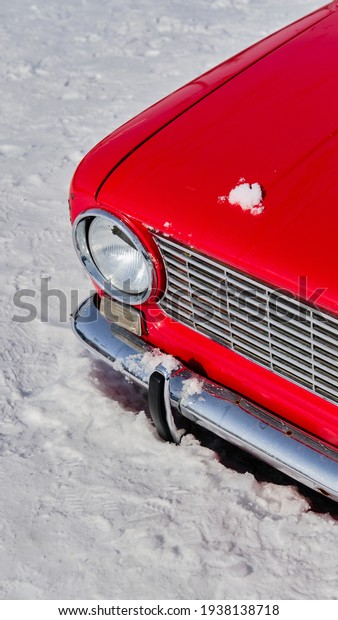Front part of Red Soviet car. Russian\
early spring. Car stuck in snow. Vertical\
image
