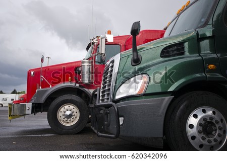 The front part of the two trucks of different styles - modern and classic green and red colors with all the attributes and details of lorries on a background of stormy gray sky