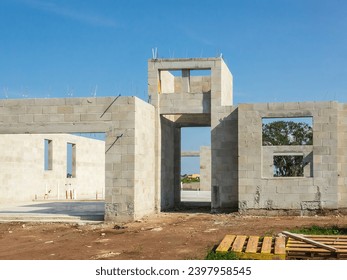 Front and partial interior view of the concrete shell of a single-family house under construction in a suburban residential development on a sunny summer morning in southwest Florida