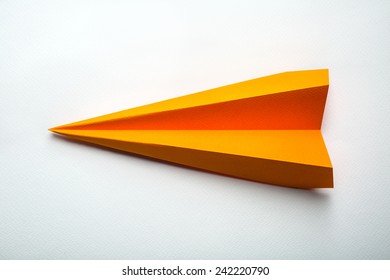 Front Photo Of Orange Origami Paper Airplane On White Paper Background