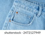 Front pocket and small pocket blue jeans pants close up, macro. Fashion concept, business, shopping, sale. Design detail, button and seams, copy space