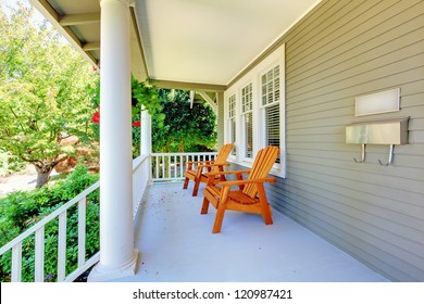 Front porch with chairs and columns of old craftsman style home.