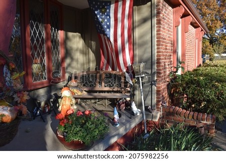 Front porch of a house with autumn decorations and an American flag